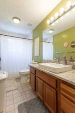 Bathroom with vanity, tile patterned floors, a textured ceiling, and toilet