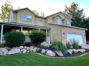 View of front facade with a garage, a porch, and a front lawn