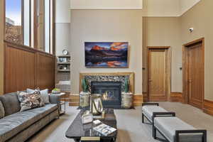 Carpeted living room with a premium fireplace and a towering ceiling