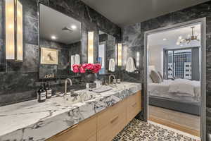 Bathroom featuring tile walls, decorative backsplash, vanity, and an inviting chandelier