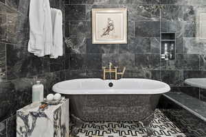 Bathroom featuring a tub to relax in and tile walls