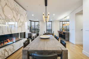 Dining area featuring a high end fireplace, a wall of windows, and light wood-type flooring