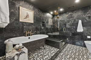 Bathroom with tile patterned floors, separate shower and tub, tile walls, and toilet