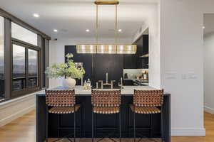 Kitchen with sink, a breakfast bar area, kitchen peninsula, light hardwood / wood-style floors, and decorative backsplash