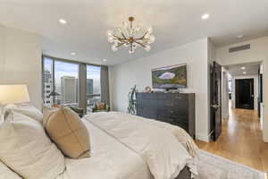 Bedroom with an inviting chandelier and light hardwood / wood-style flooring