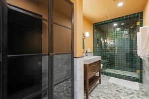 Bathroom featuring an enclosed shower, vanity, and tile walls