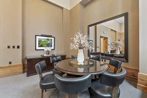 Dining room with a towering ceiling and carpet flooring