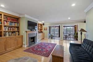 Living room with a fireplace, ornamental molding, and light wood-type flooring