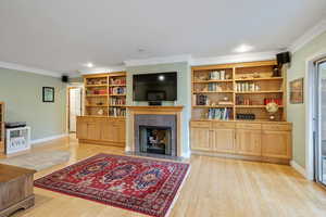 Living room with crown molding and light hardwood / wood-style flooring