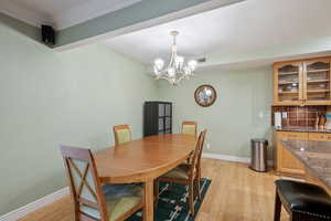 Dining room with ornamental molding, light hardwood / wood-style floors, and a chandelier