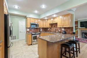 Kitchen with appliances with stainless steel finishes, a breakfast bar, sink, dark stone countertops, and kitchen peninsula