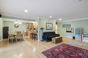 Living room featuring crown molding, a chandelier, and light wood-type flooring