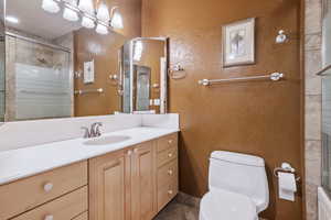 Bathroom featuring vanity, toilet, a chandelier, and a shower with door