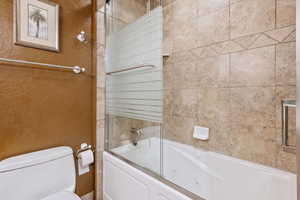 Bathroom with enclosed tub / shower combo and toilet