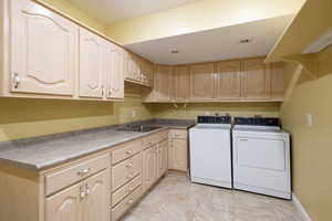 Laundry room with cabinets, independent washer and dryer, and sink