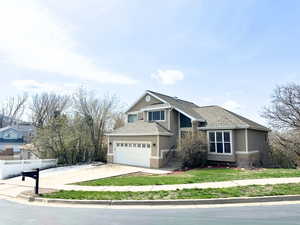 View of front of home featuring fence, stucco siding, brick siding, driveway, and roof with shingles