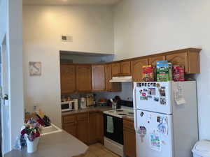 Kitchen with white appliances, light tile patterned floors, and a high ceiling