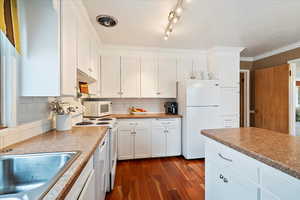 Kitchen with white cabinetry, sink, dark hardwood / wood-style flooring, decorative backsplash, and white appliances