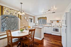 Kitchen with sink, white cabinetry, decorative light fixtures, dark hardwood / wood-style flooring, and white appliances