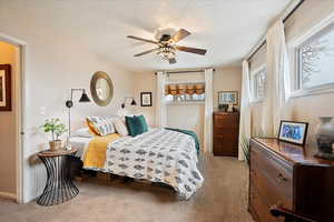 Carpeted bedroom featuring ceiling fan and a textured ceiling