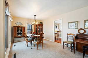 Carpeted dining area with a notable chandelier and a wealth of natural light