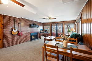 Basement Interior space with ceiling fan, brick wall, a fireplace, and carpet