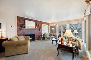 Living room featuring a fireplace, a textured ceiling, and carpet