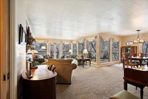 Carpeted living room featuring a textured ceiling and a notable chandelier