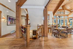 Dining room with beam ceiling, a towering ceiling, and light wood-type flooring