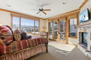 Bedroom featuring crown molding, access to exterior, a mountain view, and a stone fireplace