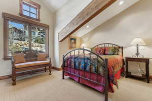 Bedroom featuring light carpet, beam ceiling, and high vaulted ceiling