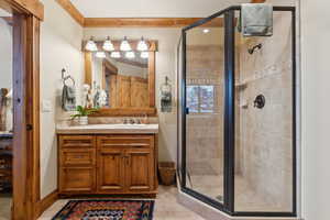 Bathroom featuring vanity, tile patterned floors, crown molding, and walk in shower