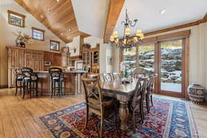 Dining room with an inviting chandelier, wood ceiling, high vaulted ceiling, and light hardwood / wood-style floors