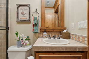 Bathroom featuring vanity, decorative backsplash, and toilet