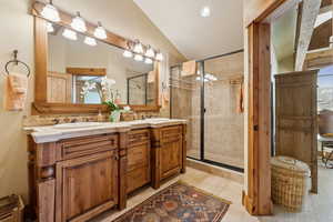 Bathroom with walk in shower, tile patterned floors, vanity, and vaulted ceiling