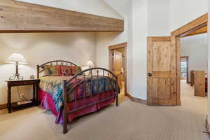 Carpeted bedroom featuring beamed ceiling and a high ceiling