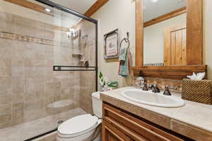 Bathroom with tasteful backsplash, vanity, ornamental molding, an enclosed shower, and toilet