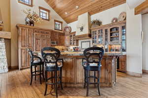 Kitchen featuring stainless steel microwave, a kitchen breakfast bar, high vaulted ceiling, and light hardwood / wood-style flooring