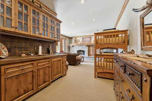 Kitchen with a stone fireplace, tasteful backsplash, sink, crown molding, and light carpet