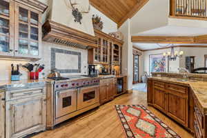 Kitchen with sink, double oven range, light hardwood / wood-style floors, decorative backsplash, and custom exhaust hood