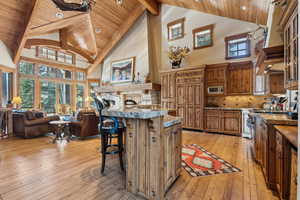 Kitchen featuring beam ceiling, a kitchen breakfast bar, stainless steel microwave, light hardwood / wood-style floors, and a kitchen island