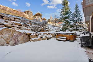 Yard covered in snow with a hot tub