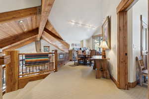 Hall featuring carpet, vaulted ceiling with beams, track lighting, and wooden ceiling