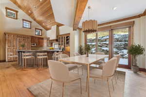 Dining area with light wood-style flooring and high vaulted ceiling