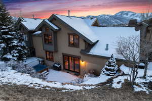 Snow covered rear of property with a mountain view