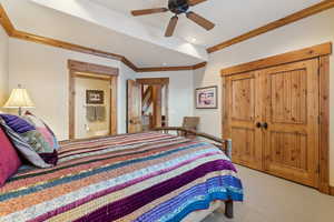 Bedroom with ornamental molding, light carpet, ensuite bathroom, and ceiling fan