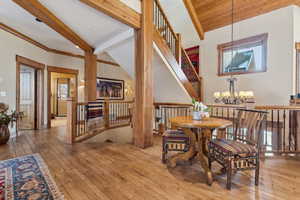 Dining room with wood-type flooring, lofted ceiling with beams, and a notable chandelier