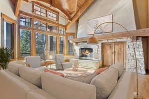 Living room with a wooden ceiling with exposed beams, high vaulted ceiling, hardwood / wood-style floors, and a fireplace