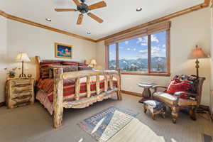 Bedroom featuring crown molding, light colored carpet, a mountain view, and ceiling fan