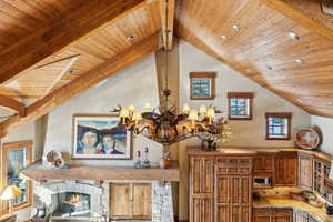 Interior details with wood ceiling, a stone fireplace, a notable chandelier, and beamed ceiling